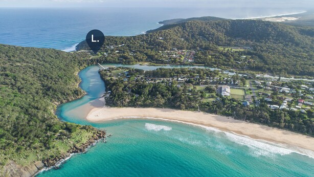 Vista aérea de una zona costera con playa, río y una colina boscosa.