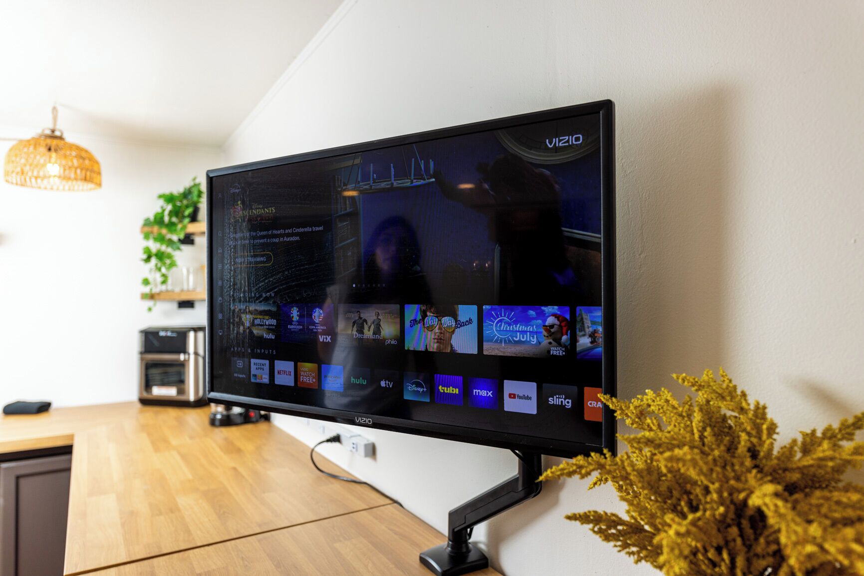 Un televisor Vizio montado en una pared que muestra varios servicios de transmisión y una película en reproducción.