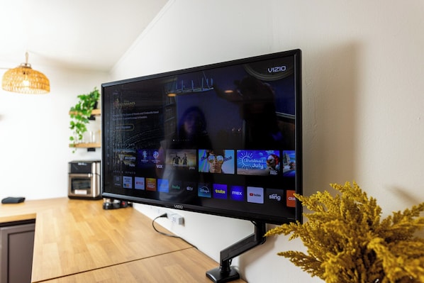 A Vizio TV mounted on a wall displaying various streaming services and a movie playing.