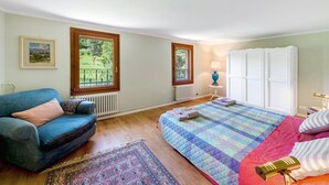 Ein Schlafzimmer mit Bett, Sofa, Heizkörper, Fenster und Tür.