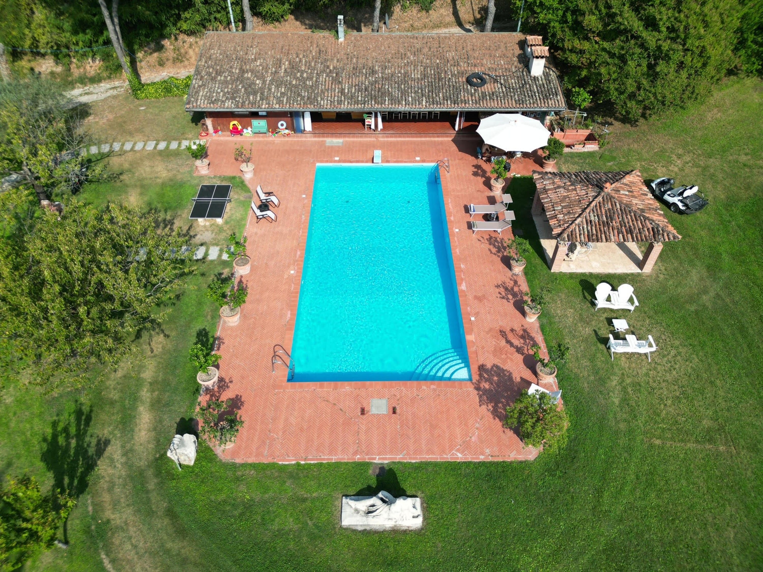 Vue aérienne d’une propriété dotée d’une piscine, d’un espace salon extérieur et d’un patio couvert.