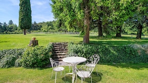 A garden with a white metal table and chairs, surrounded by lush greenery and trees. - Suite with View on 25-Hectare Estate, Pool & Park – Affi, Lake Garda (Affi)