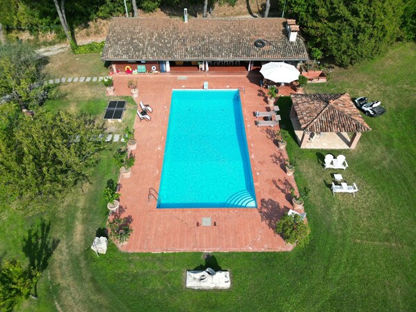 An aerial view of a property with a swimming pool, outdoor seating, and a covered patio area.
