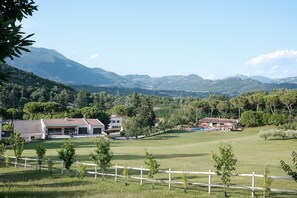 Un quartier résidentiel avec des maisons, une cour clôturée et des montagnes en arrière-plan.