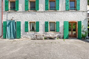 Un bâtiment doté de nombreuses fenêtres, d’une porte et d’un banc devant l’entrée.