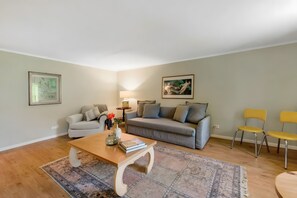 Un salon comprenant un canapé, deux fauteuils, une table basse et un tapis.