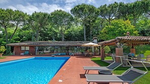A swimming pool with lounge chairs, a covered patio, and a brick building with a tiled roof. - Cavallina Retreat - Guest House with Private Pool, Garden, and Wi-Fi (Affi)