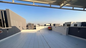 Terraza en la azotea con suelo de baldosas y vistas de edificios circundantes.