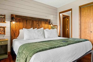 Une chambre à coucher avec une tête de lit en bois, une couverture verte et une lampe de chevet.