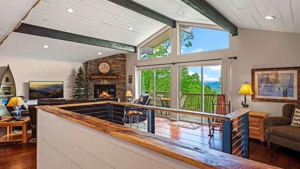 A spacious living area with a fireplace, large windows, and a balcony.
