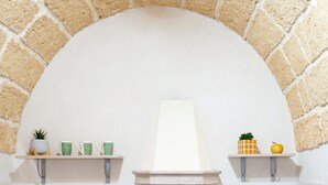 A room with a white wall, a brick arch, and two shelves with decorative items.