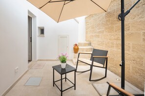 A small patio with a table, chair, and umbrella.