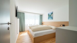 Quarto de hotel moderno com cama de madeira, televisão de tela plana e um quadro na parede.