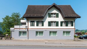 Um edifício de dois andares com telhado empena, várias janelas com persianas e fachada plana.