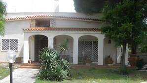 A building with a tiled roof, arched windows, and a paved entrance.