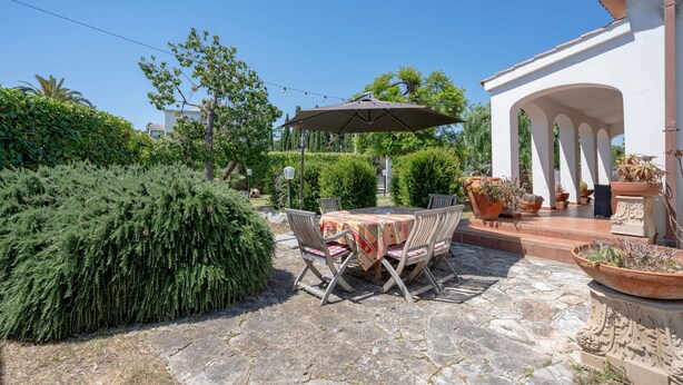 A patio with stone flooring, a table with chairs, and a large umbrella.