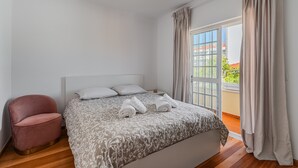 Un dormitorio con una cama, una silla y vistas al exterior.