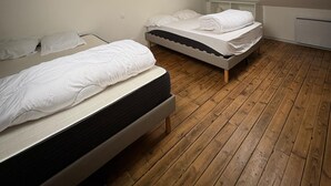 Un dormitorio con dos camas, suelo de madera, un tragaluz y un radiador blanco.