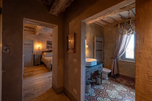 A bedroom with a bed, a bedside table, a nightstand, a window with curtains, and a door labeled 'impadone'.