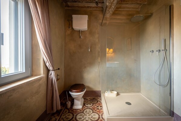 Un baño con inodoro, ducha y ventana.