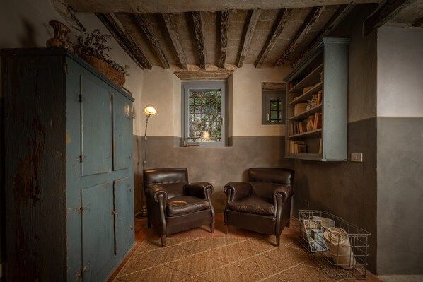 Une pièce comprenant deux fauteuils en cuir, un meuble en bois, une fenêtre donnant sur un beau paysage et une bibliothèque.
