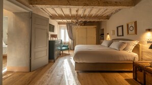 Een slaapkamer met een houten plafond, een bed, een kaptafel, een stoel en een kroonluchter.