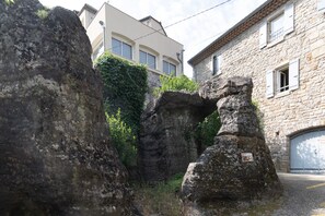 A stone building with a large rock formation in front, a garage door, and a building with windows in the background.
