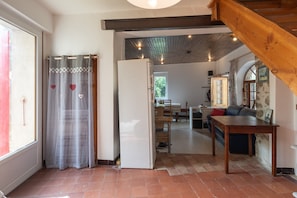 Una cucina con frigorifero, soffitto in legno e zona pranzo con tavolo e sedie.