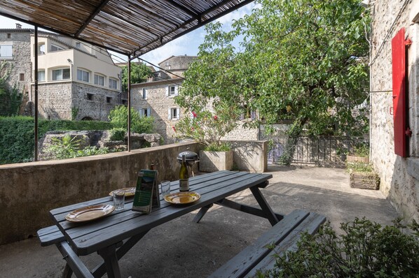 An outdoor patio with a table set for dining, surrounded by stone walls and greenery.