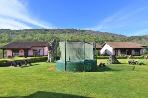 A grassy area with a trampoline, a picnic table, and a bicycle.