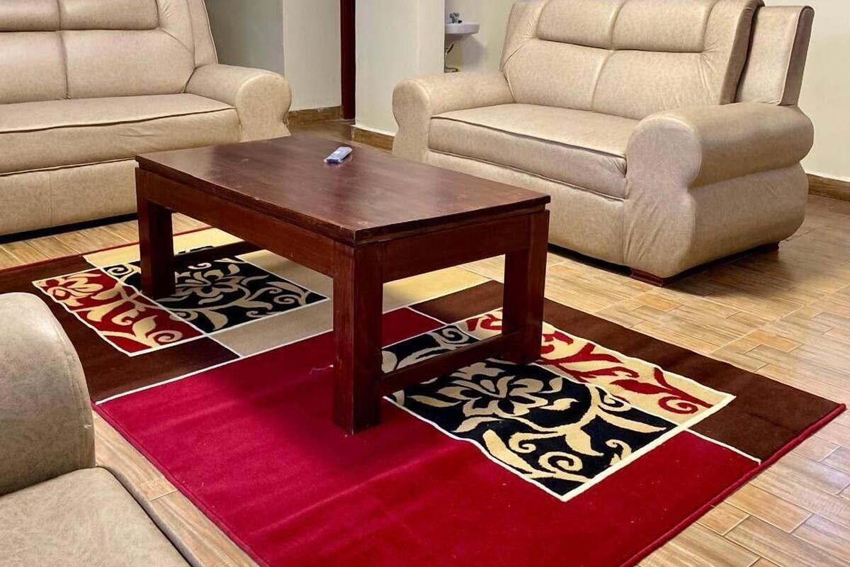 A living room with two beige sofas, a wooden coffee table, and patterned rugs.