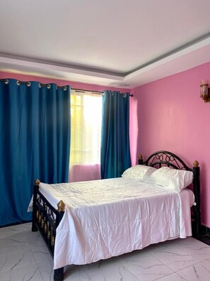Ein Schlafzimmer mit Bett, Vorhängen und einem Fenster.