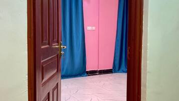Una habitación con puerta de madera, paredes rosas y cortinas azules.