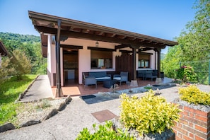 A modern house with a covered patio, outdoor seating, and a garden.