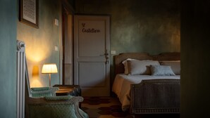 Een kamer met een bed, een nachtkastje, een lamp, een deur met de tekst 'Il Castellare' en een kamer met een patroon vloer.