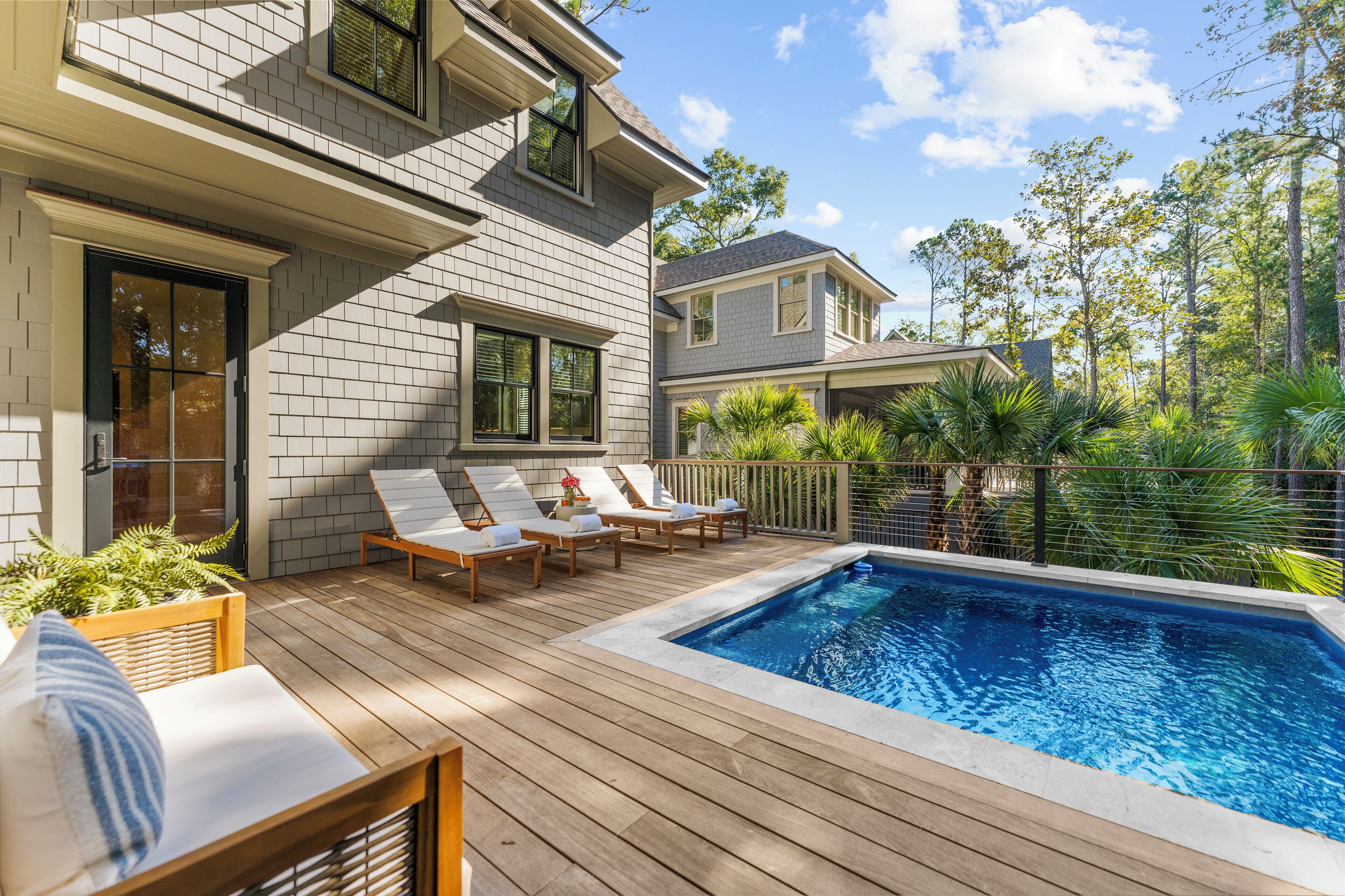 A poolside area with wooden deck, lounge chairs, and a swimming pool.
