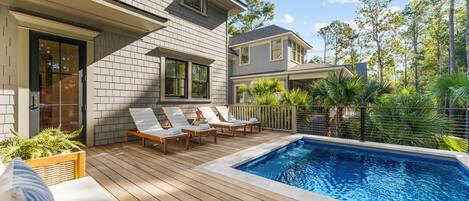 A poolside area with wooden deck, lounge chairs, and a swimming pool.