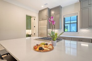 A modern kitchen with a large island, stainless steel appliances, and a fruit platter. - New Build with pool in central neighborhood (Kiawah Island)