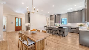 A spacious kitchen with a central island, dark cabinets, and a modern chandelier. - New Build with pool in central neighborhood (Kiawah Island)