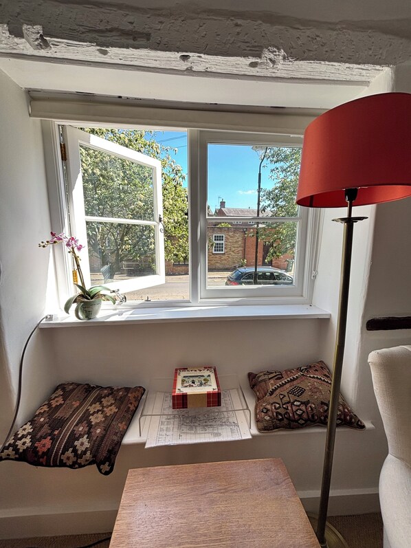 A room with a window seat, a lamp, and a small table. - 16th century lace makers cottage in the heart of rural England (Gawcott)