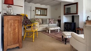 Een gezellige woonkamer met een houten kast, een gele stoel, een bank en een open haard.