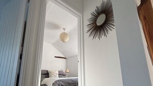 Een slaapkamer met een bed, een stoel, een spiegel en een hanglamp.