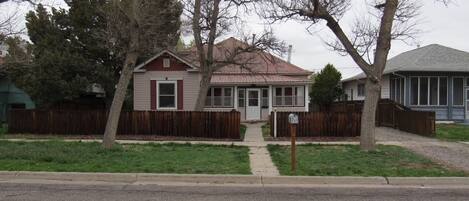 A single-story house with a front porch, a picket fence, and a mailbox.