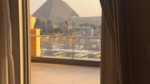Uitzicht op een piramide vanaf een balkon met een glazen reling.
