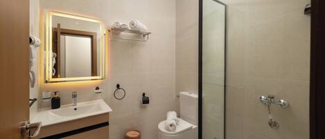 Une salle de bain moderne avec une douche à l’italienne en verre, un meuble-lavabo avec un miroir et des toilettes.