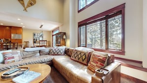A spacious living room with a large sectional sofa, a dining area with wooden furniture, and a kitchen with modern appliances.