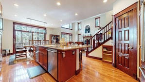 A spacious kitchen with a large island, wooden flooring, and a staircase leading to another level.