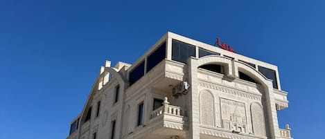 Un edificio de varios pisos con una entrada destacada que presenta intrincados grabados y un reloj.
