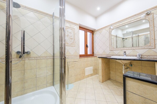 Un ba ño con ducha, lavabo, espejo y puerta.