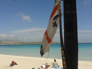 A beach scene with a flag, a sandy shore, and a distant mountain.